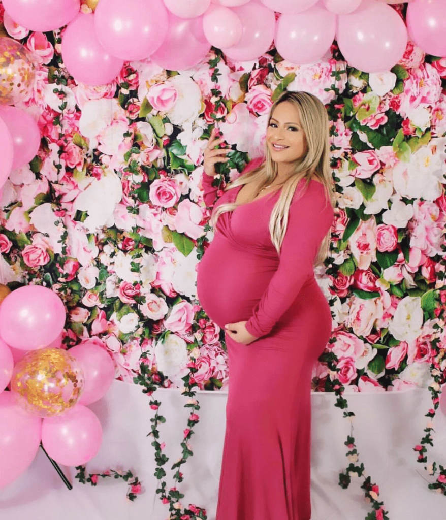 Beautiful Pregnant Mom in Pink Dress, standing in front of gorgeous Rose Floral Wall backdrop