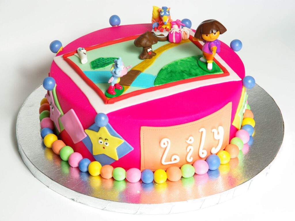 Colorful Dora the Explorer birthday cake with adorable pink frosting, colorful M&M choco candies, Dora, Boots and Map figurines